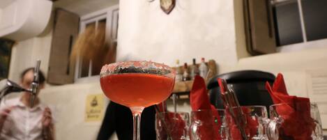 Eine Bar mit einem Cocktailglas, Gläsern und einem Hirschgeweih an der Wand.