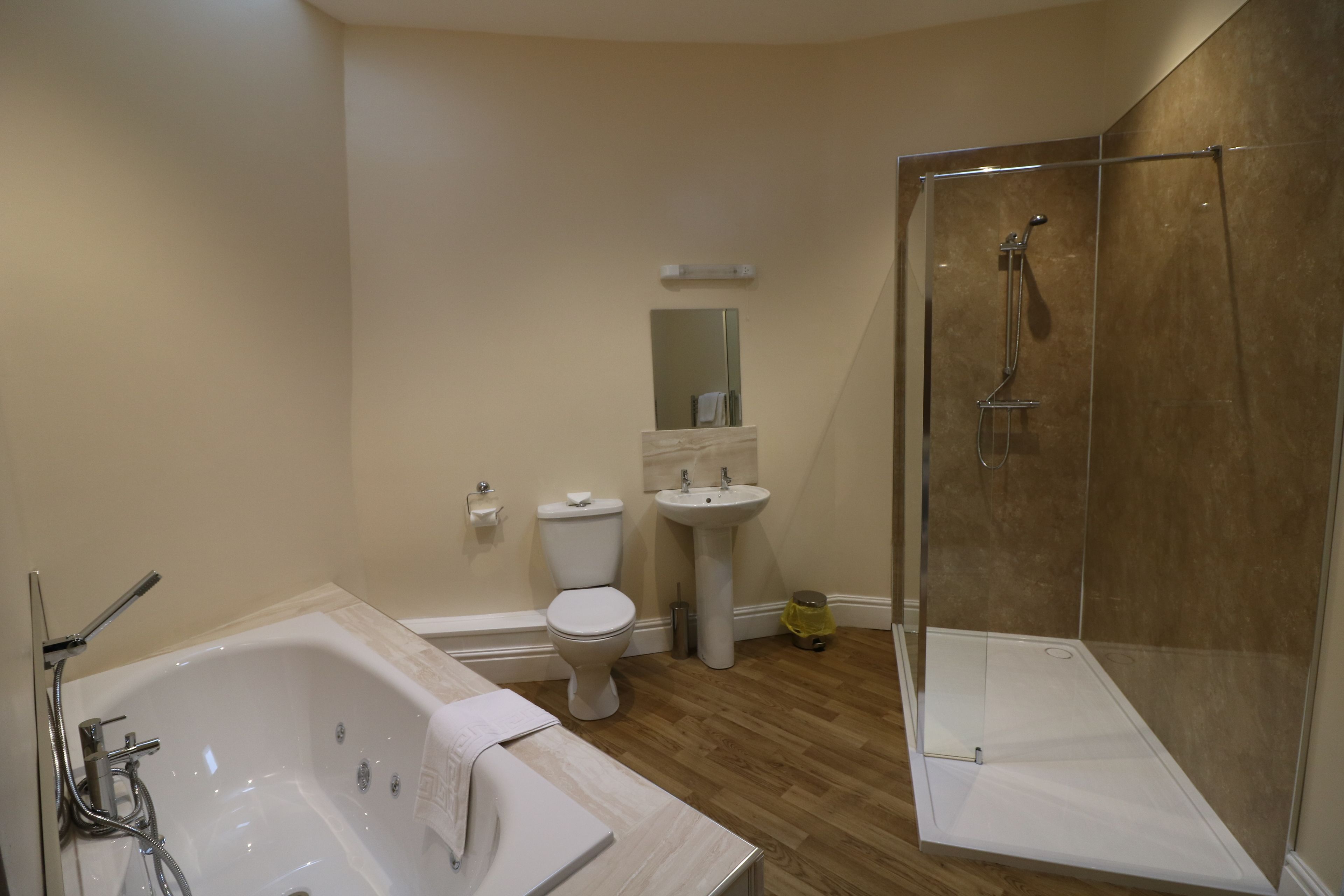 A modern bathroom with a bathtub, toilet, sink, and glass-enclosed shower.