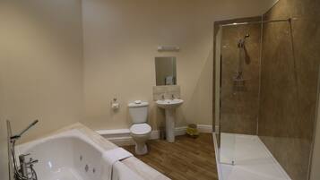 A modern bathroom with a bathtub, toilet, sink, and glass-enclosed shower.