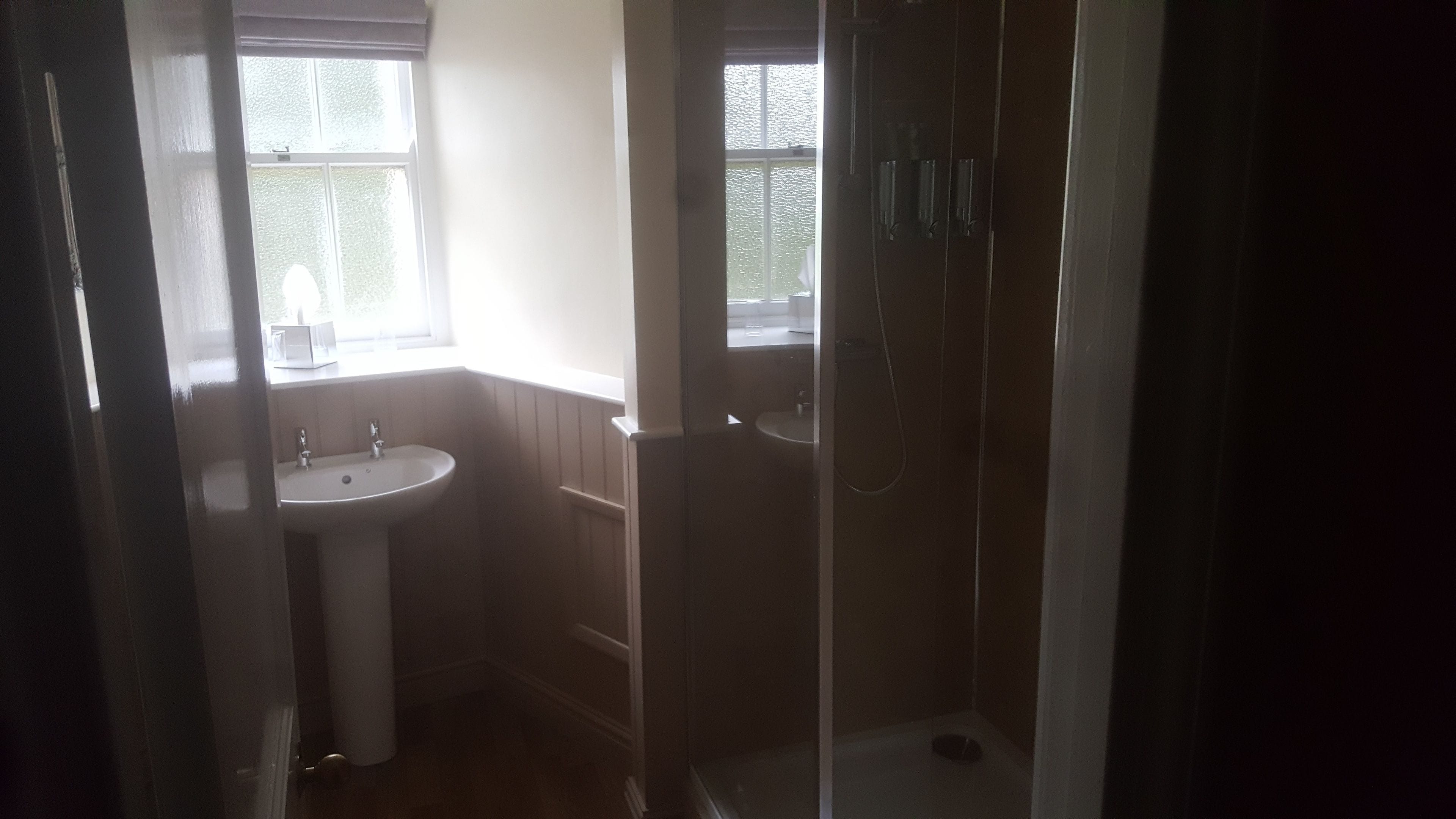 Een badkamer met een wastafel, een raam en een douche.