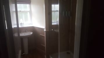Een badkamer met een wastafel, een raam en een douche.