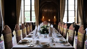 A formal dining room with a long table set for a meal, flanked by chairs with patterned upholstery and gold sashes. - Appleby Castle (Appleby-in-Westmorland)