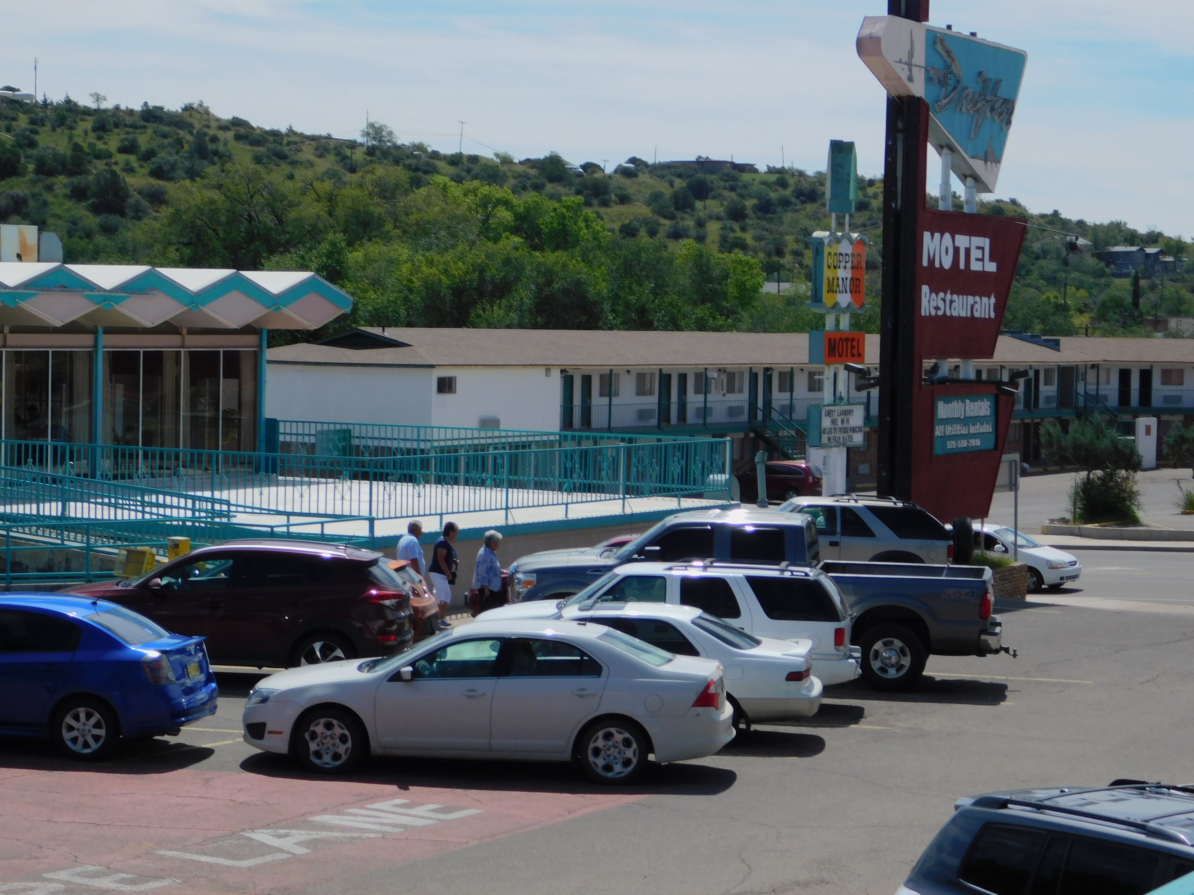 A motel with a signboard indicating it offers monthly rentals and a restaurant.