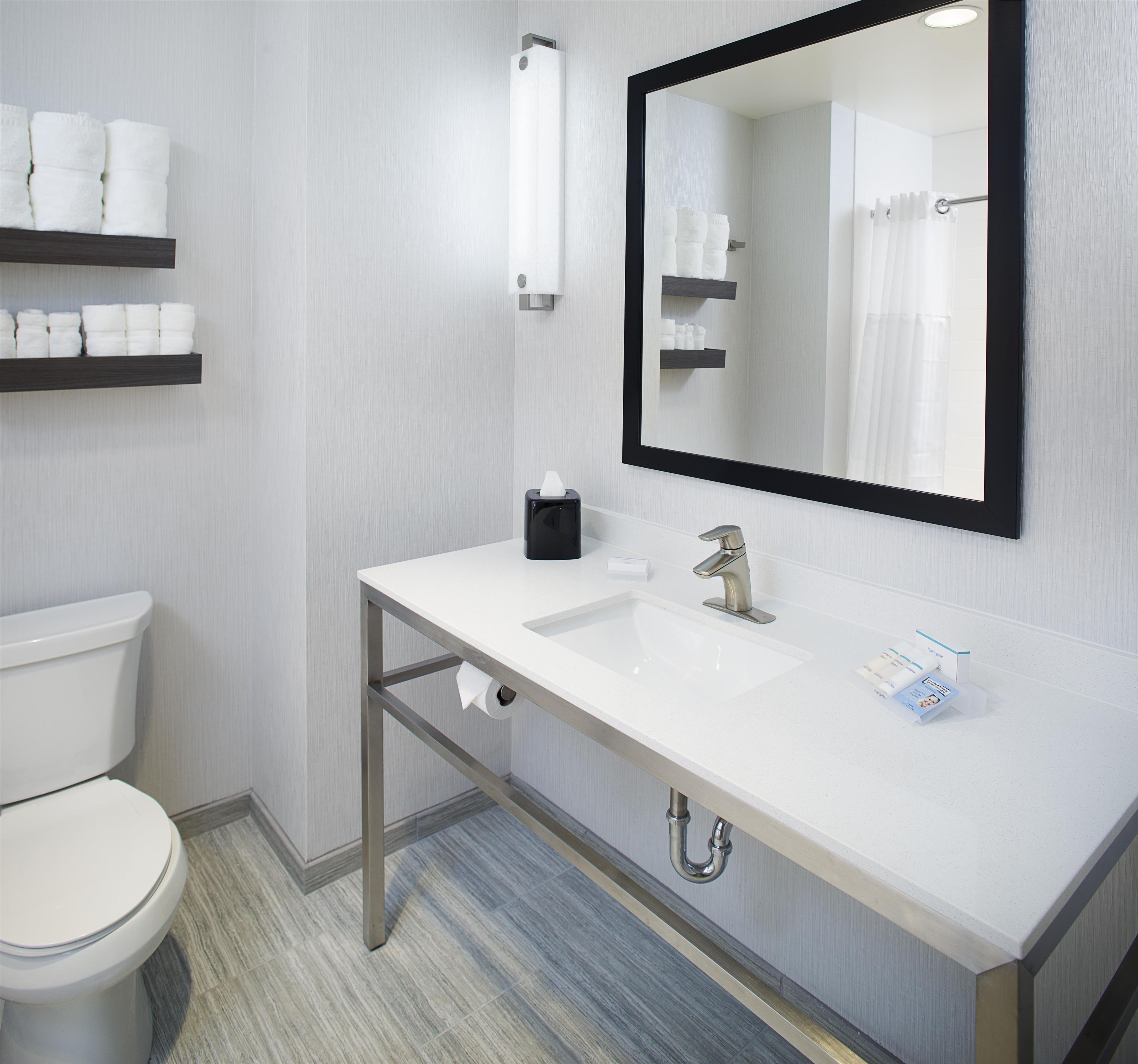 A modern bathroom with a white sink, a mirror, and a toilet.