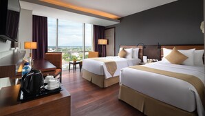A hotel room with two beds, a desk with a coffee maker, a chair, and a view of the city. - Best Western Plus Coco Palu (Palu)