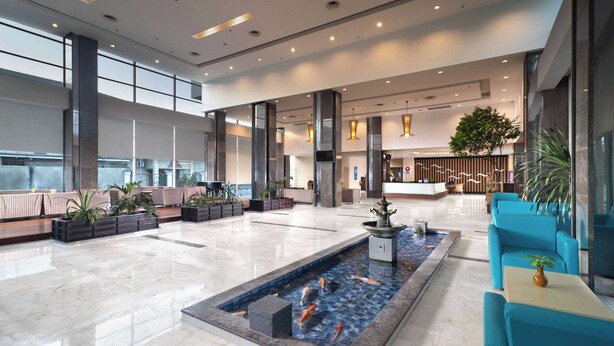 A spacious lobby with a koi pond, seating areas, and a reception desk. - Best Western Plus Coco Palu (Palu)