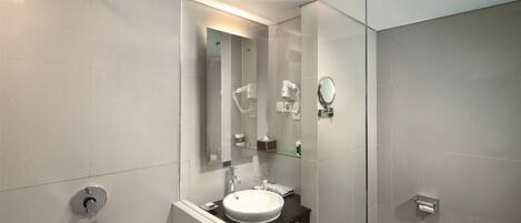 A modern bathroom with a glass shower enclosure, a round sink, and a mirror above it.