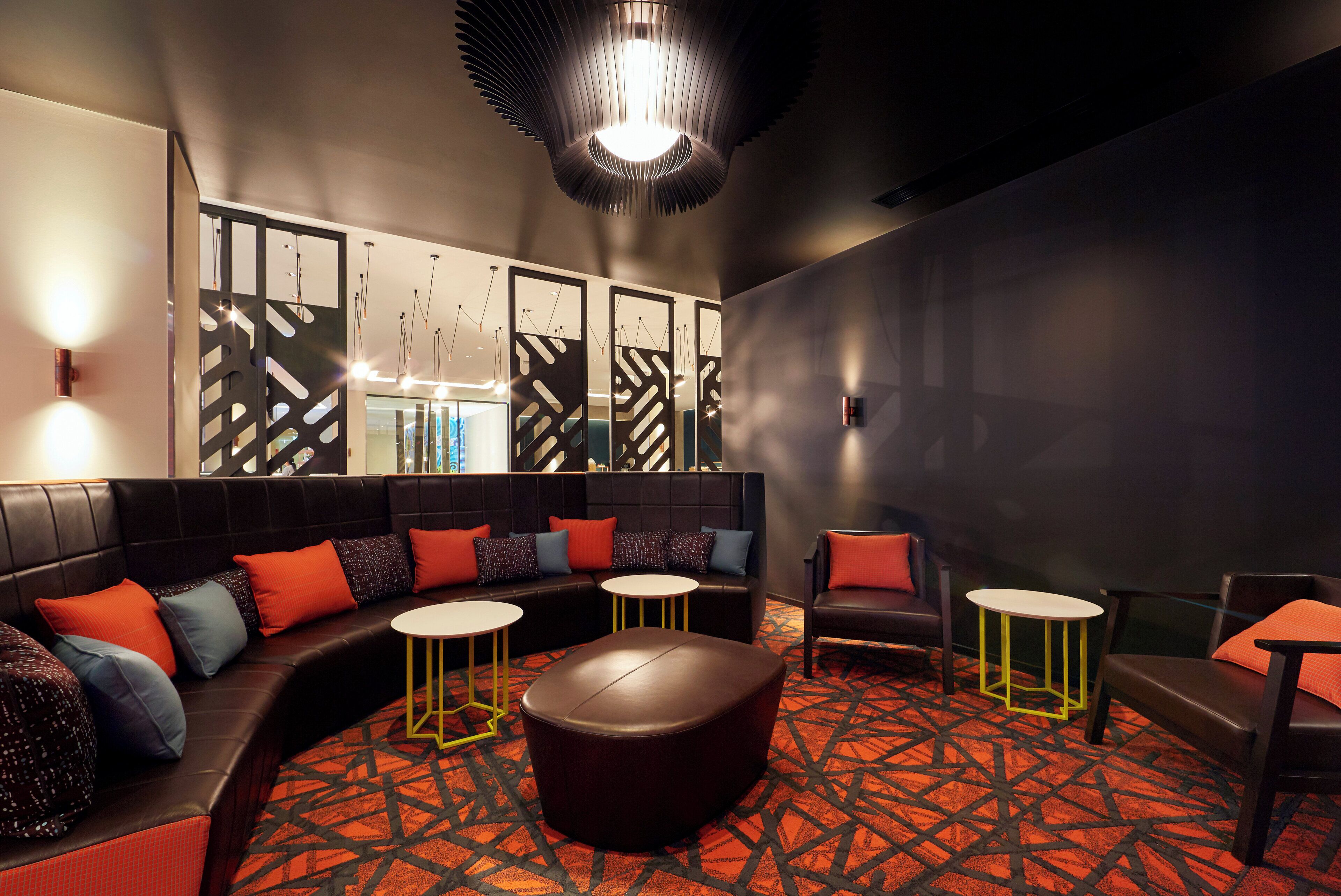 A modern lounge area with a curved sofa, round tables, and a unique ceiling light fixture.