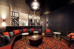 A modern lounge area with a curved sofa, round tables, and a unique ceiling light fixture.