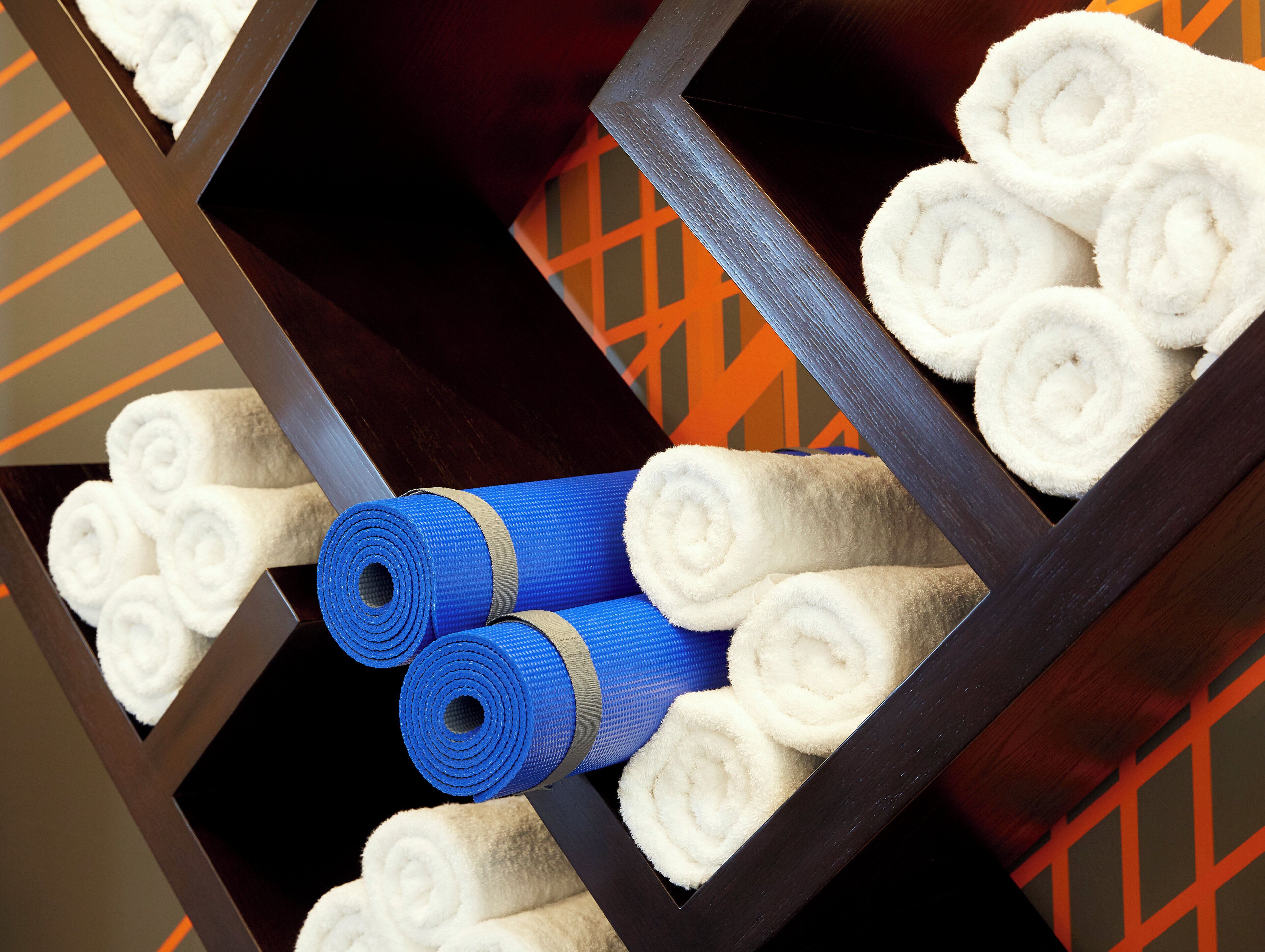 Een houten plank met opgerolde witte handdoeken en blauwe yogamatten.
