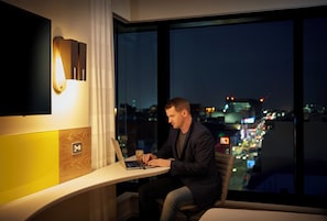 A man working on a laptop at a desk with a city view.