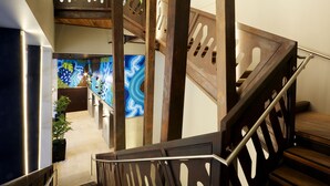 A multi-level interior with a wooden staircase, a reception area with colorful wall art, and a modern design aesthetic. - Holiday Inn Express Adelaide City Centre by IHG (Adelaide)