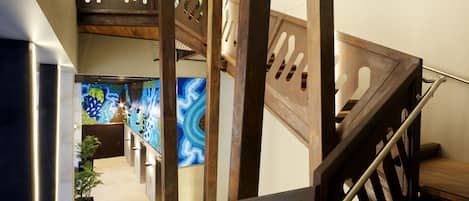 A multi-level interior with a wooden staircase, a reception area with colorful wall art, and a modern design aesthetic.