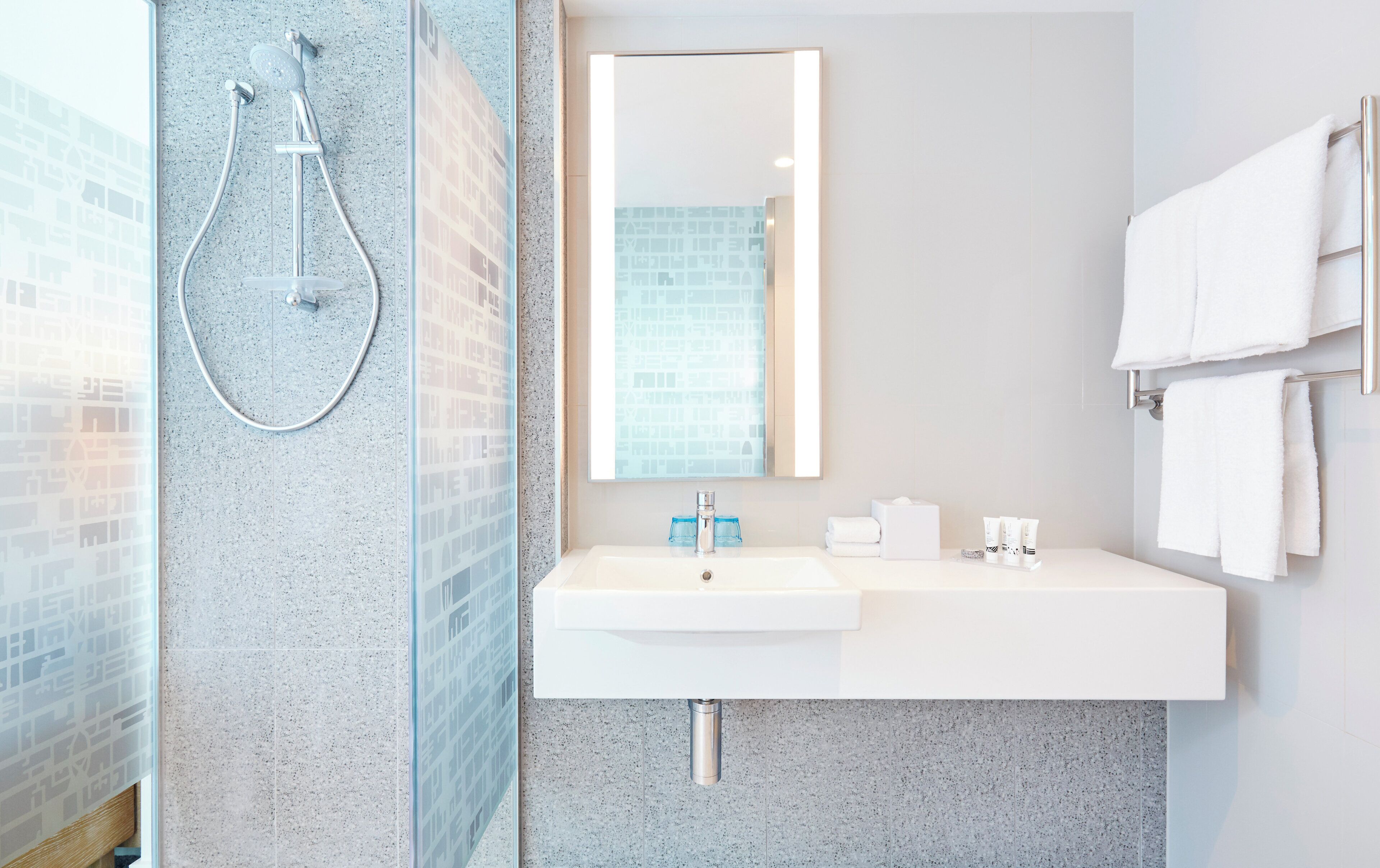 A modern bathroom with a glass shower enclosure, a white sink, and a mirror.