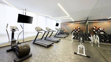 A modern gym with treadmills, elliptical machines, and a variety of dumbbells.