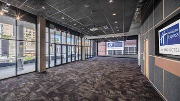 A hotel corridor with large windows, a carpeted floor, and a sign for Holiday Inn Express.