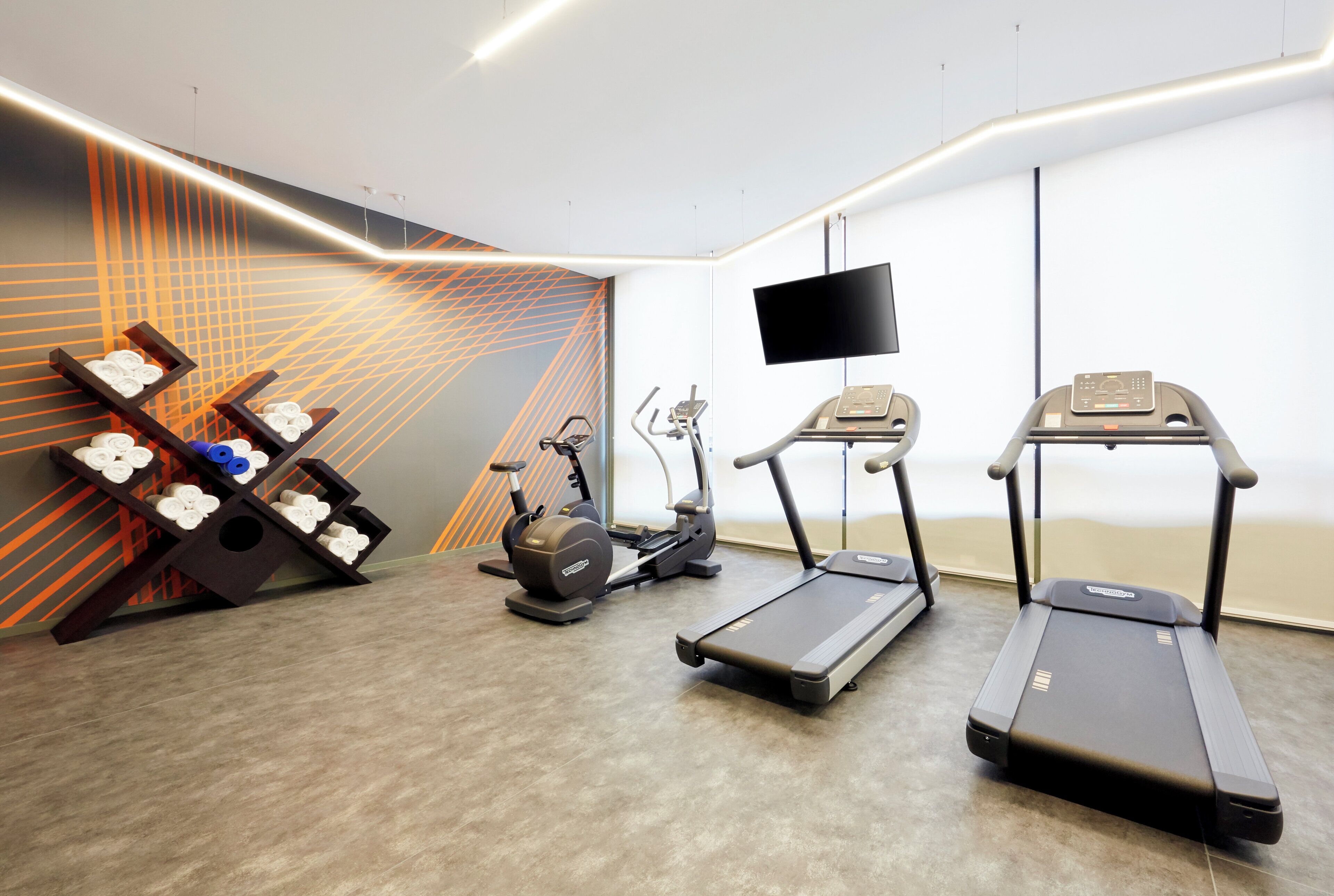 Un gimnasio con equipo de ejercicio, incluyendo una caminadora, elíptica y bicicleta estática.
