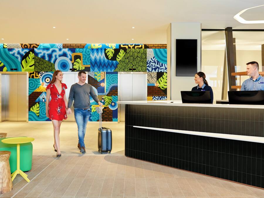 Vestíbulo de hotel con una recepción, un mural abstracto grande y un diseño moderno.