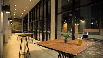An indoor seating area with tables and chairs, a glass partition, and a potted plant.