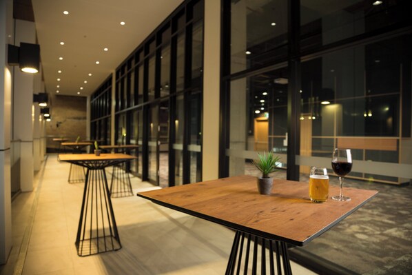 An indoor seating area with tables and chairs, a glass partition, and a potted plant.
