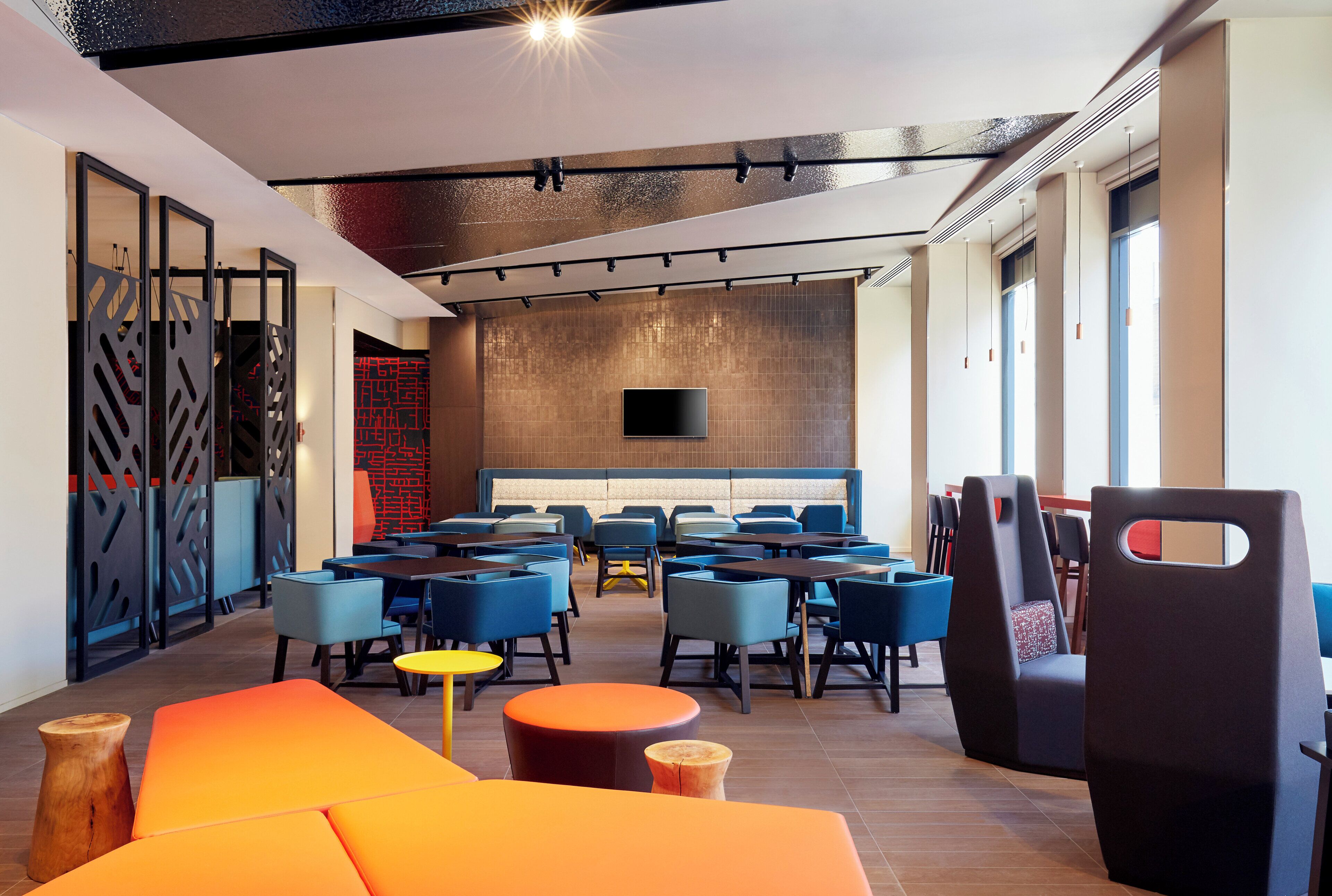 A modern interior with a seating area, tables, and a large screen.