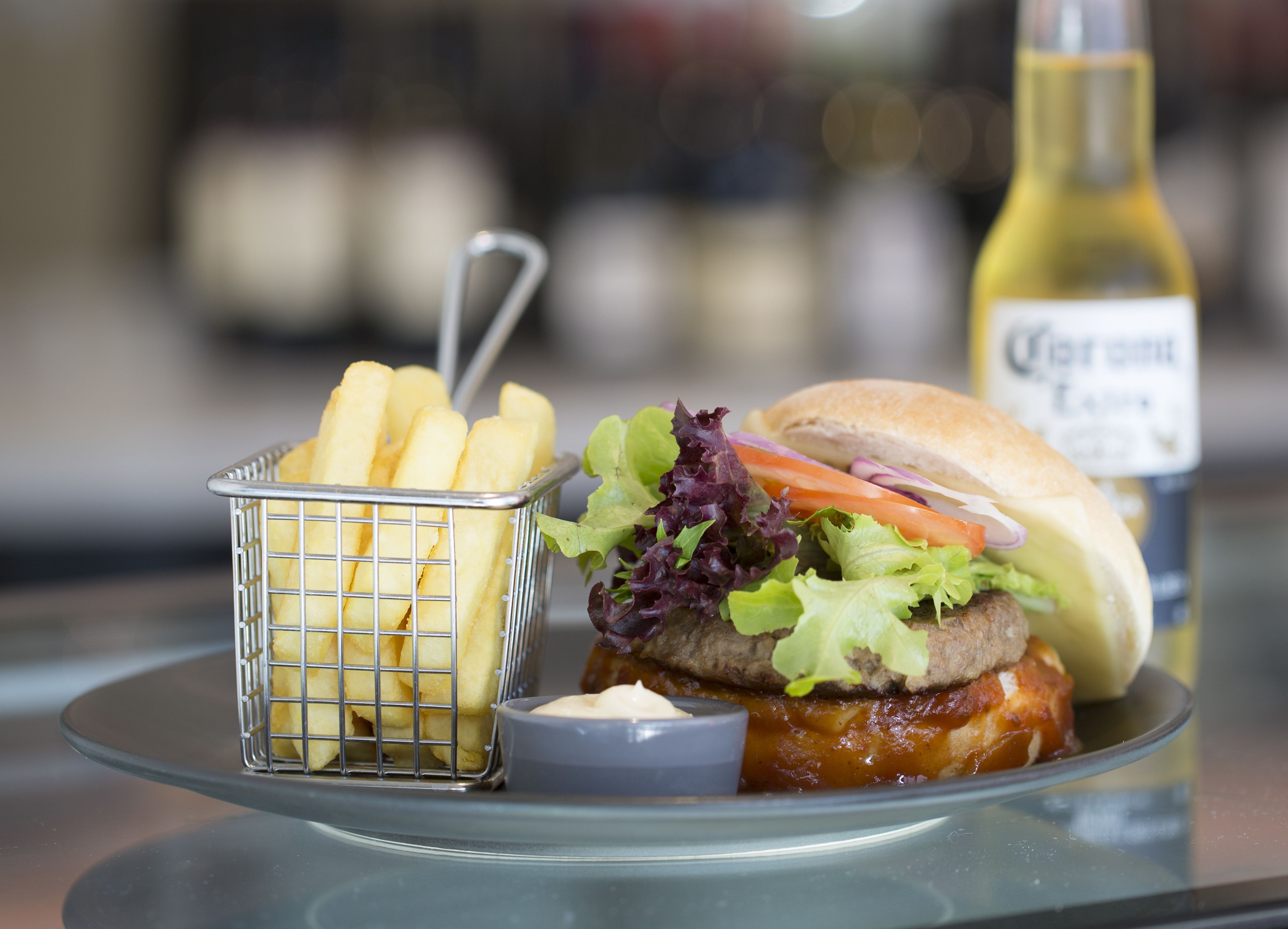 A meal consisting of a burger with lettuce, tomato, and a bun, accompanied by a small basket of fries and a side of sauce.