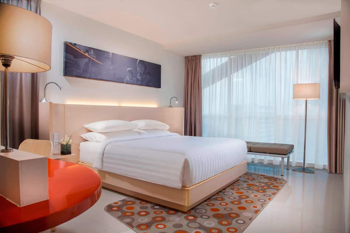 Una habitación de hotel moderna con una cama grande, un escritorio y una silla.