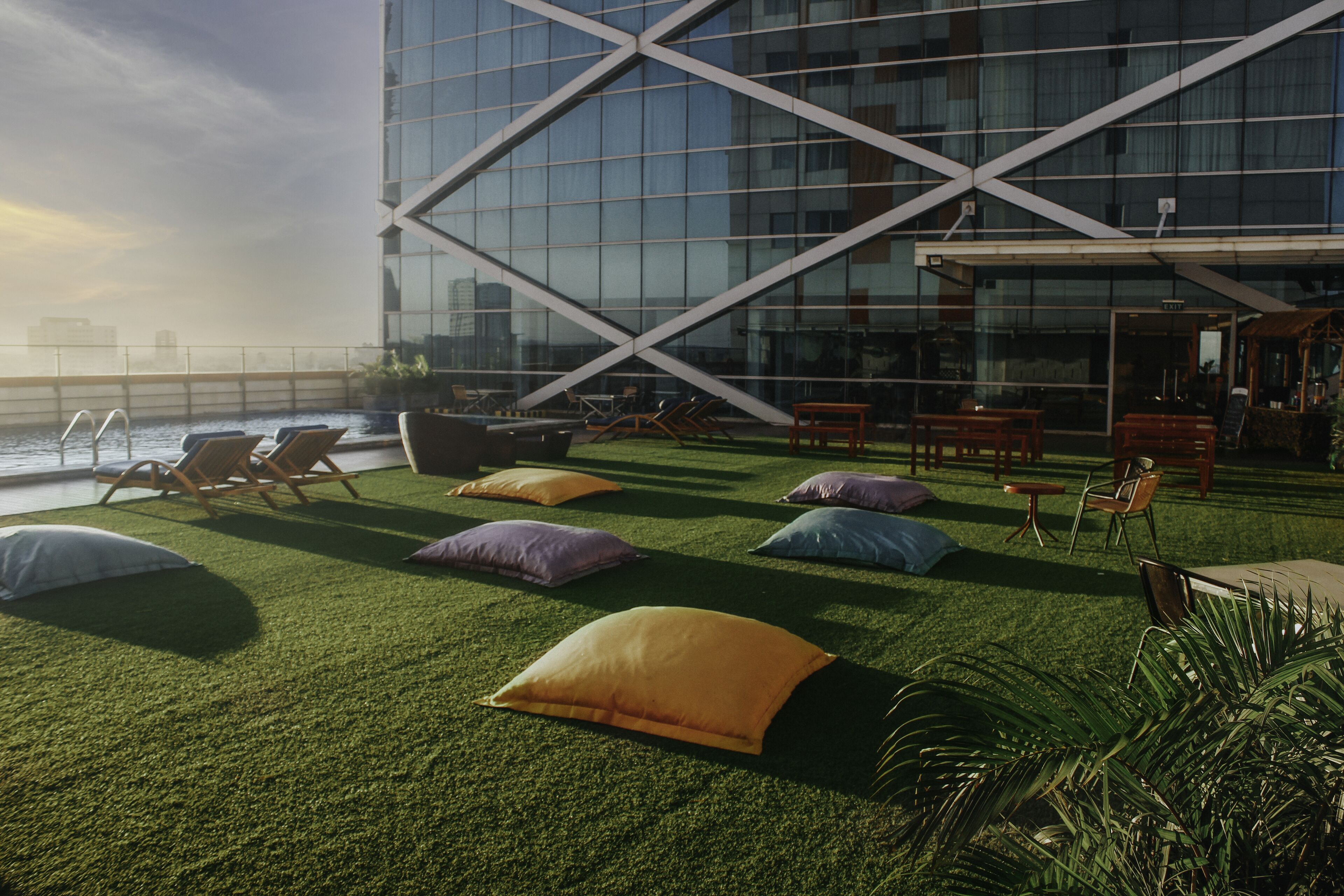 Una terraza en la azotea con césped artificial, sillones de descanso y cojines.