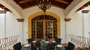 A dining area with a round glass table, black chairs, and a large arched window.