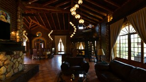 A spacious lobby with a stone fireplace, leather sofas, and a high ceiling with exposed beams.