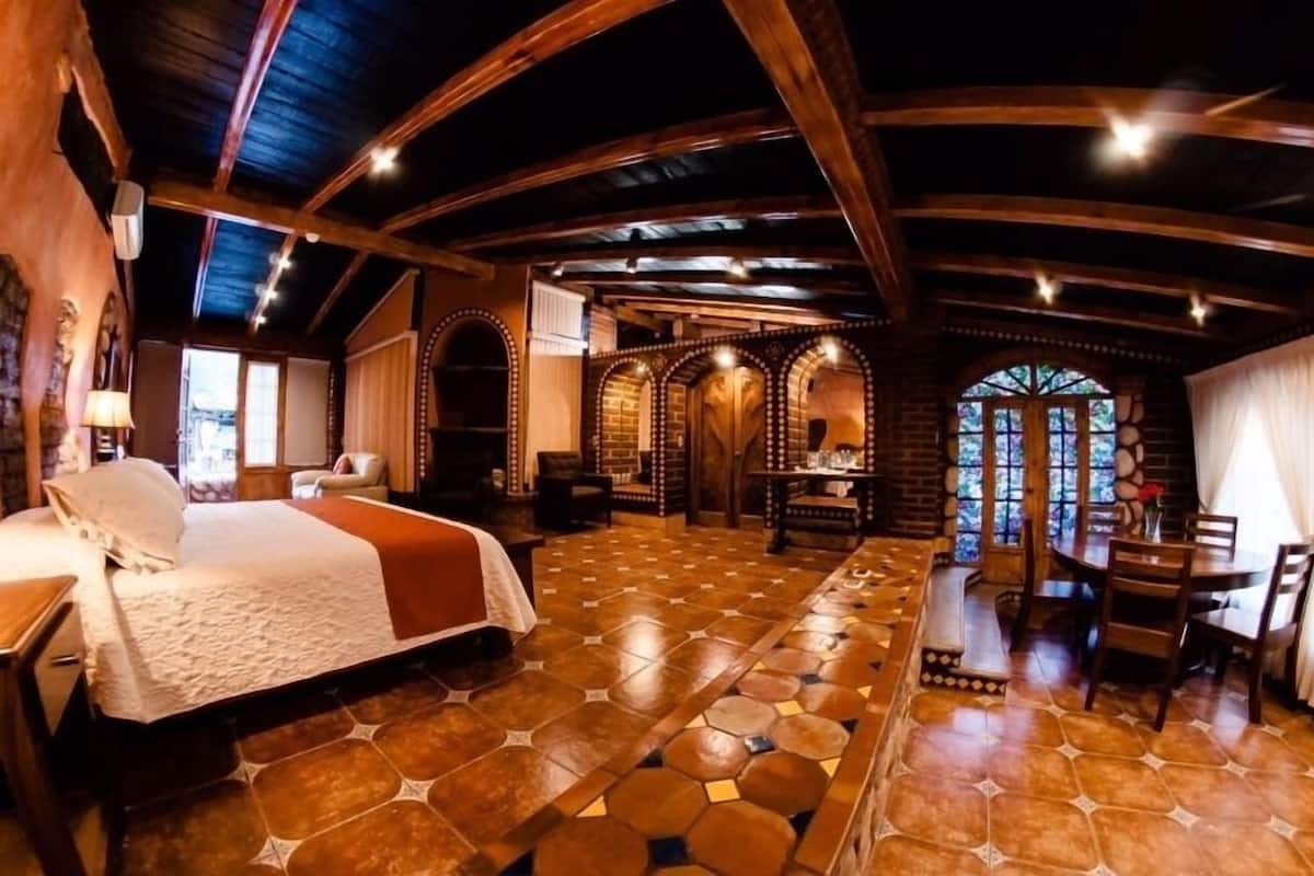 Una habitación amplia con una cama grande, una mesa de comedor y piso de baldosas de piedra.