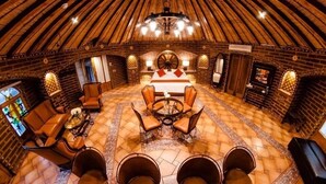A cozy, circular room with a large bed, multiple seating areas, and a unique wooden dome ceiling.