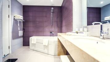 A modern bathroom with a bathtub, a shower, and a vanity with a mirror.