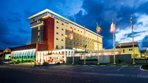 A hotel with a prominent "Golden Tulip" sign, multiple flags, and a well-lit entrance. - Golden Tulip Le Diplomate Cotonou (Cotonou)