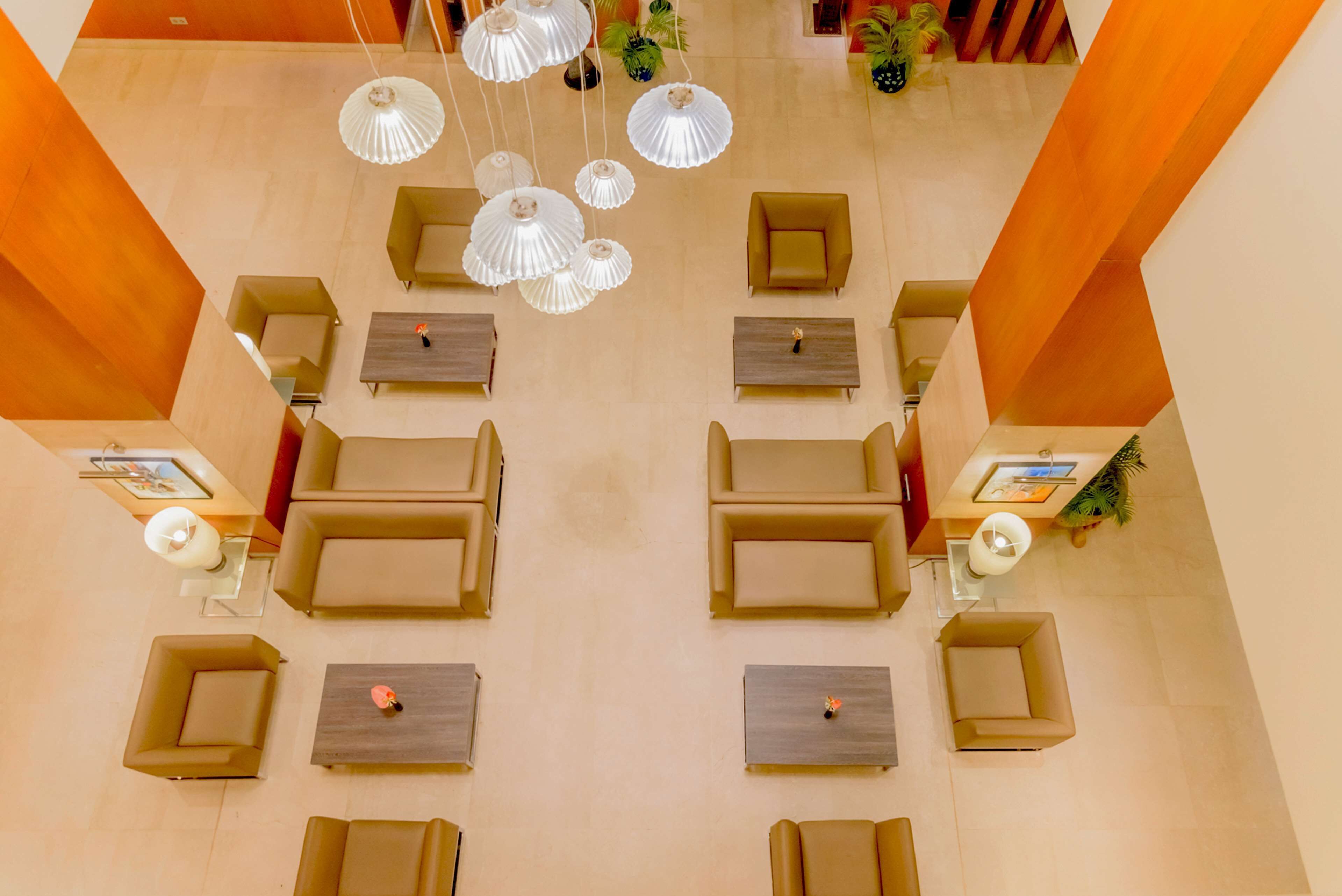 A lobby with multiple seating areas, tables, and hanging lamps.