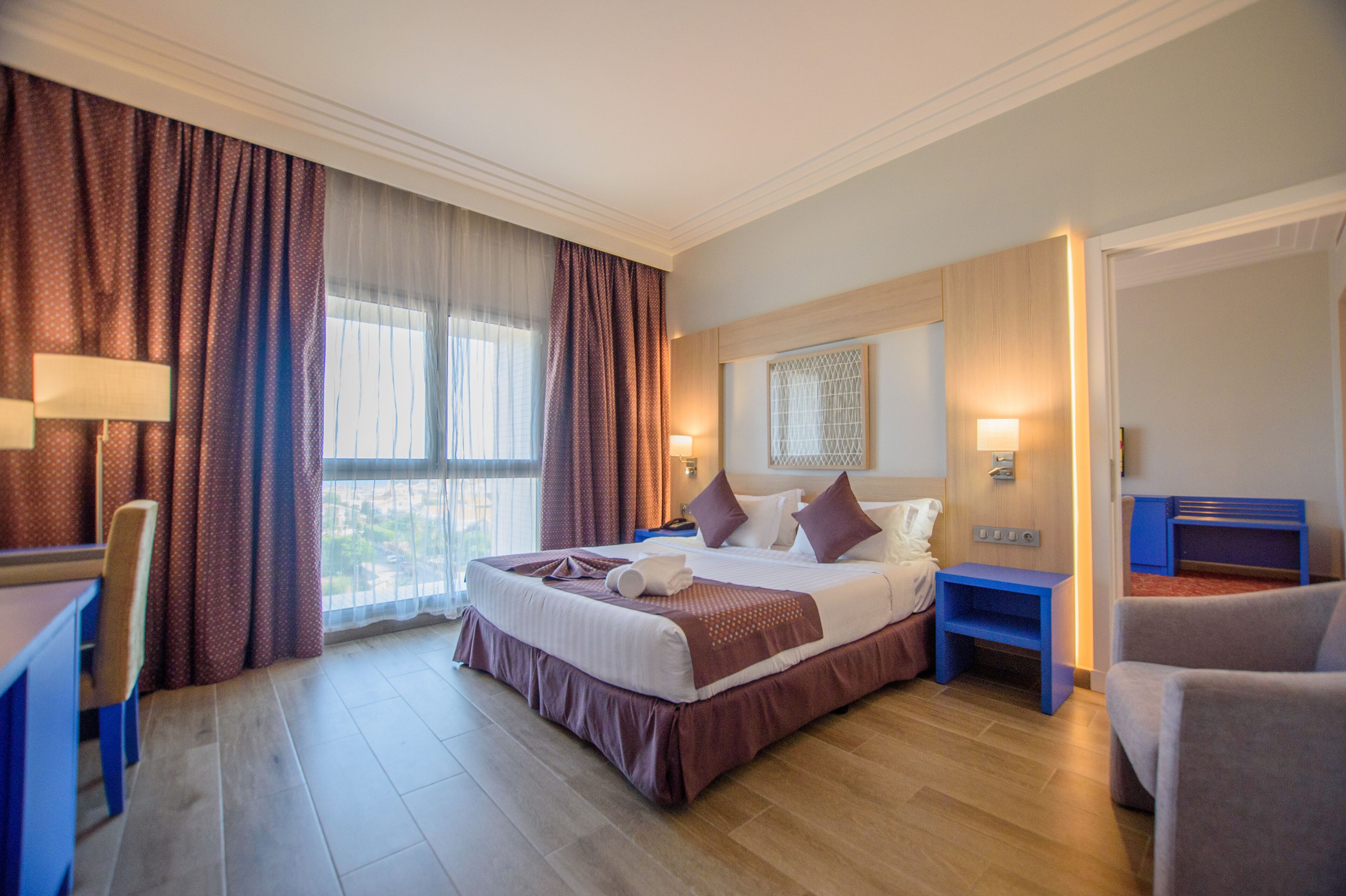 Camera d'albergo con un letto grande, una scrivania, una sedia e vista sull'esterno.