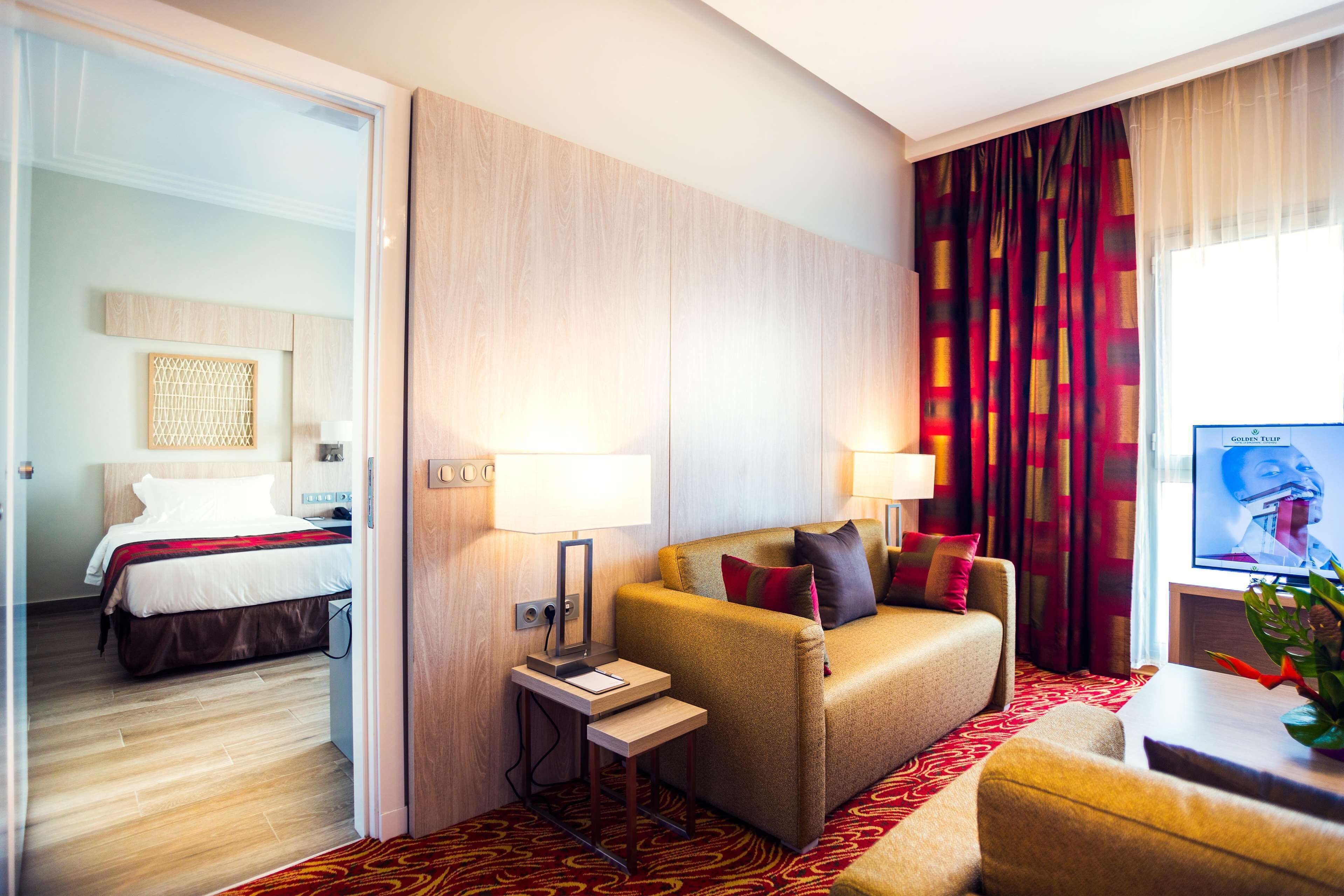 Una habitación de hotel con cama, sofá, una mesita y televisión.