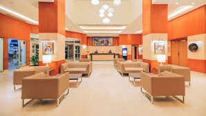 A hotel lobby with a reception desk, seating area, and artwork on the walls. - Golden Tulip Le Diplomate Cotonou (Cotonou)