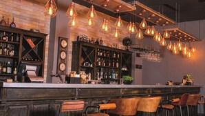 A bar with multiple hanging light fixtures, a bar counter, and several bar stools. - Golden Tulip Le Diplomate Cotonou (Cotonou)