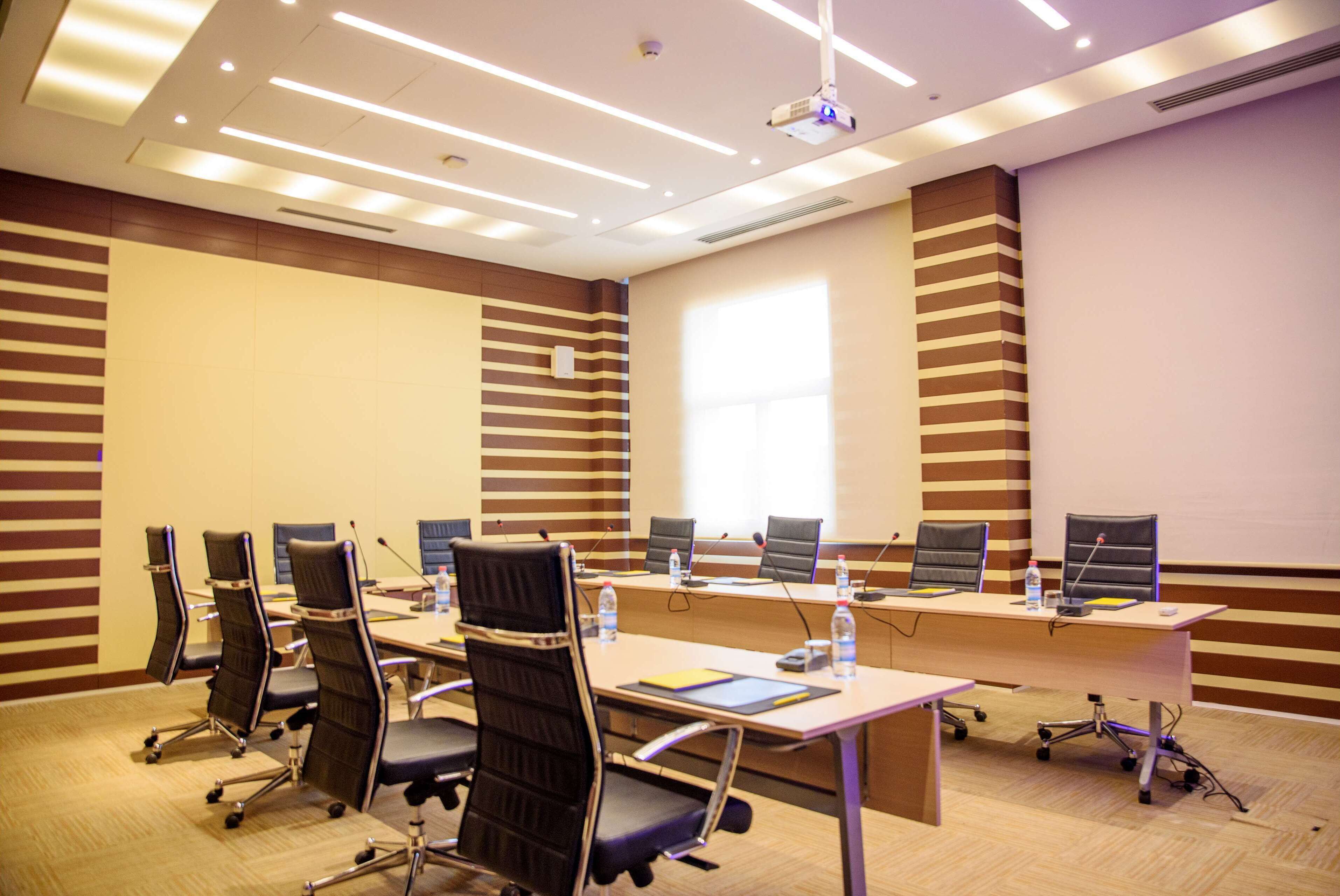 A conference room with a long table, multiple chairs, a projector, and a whiteboard.