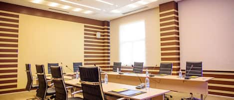 A conference room with a long table, multiple chairs, a projector, and a whiteboard.