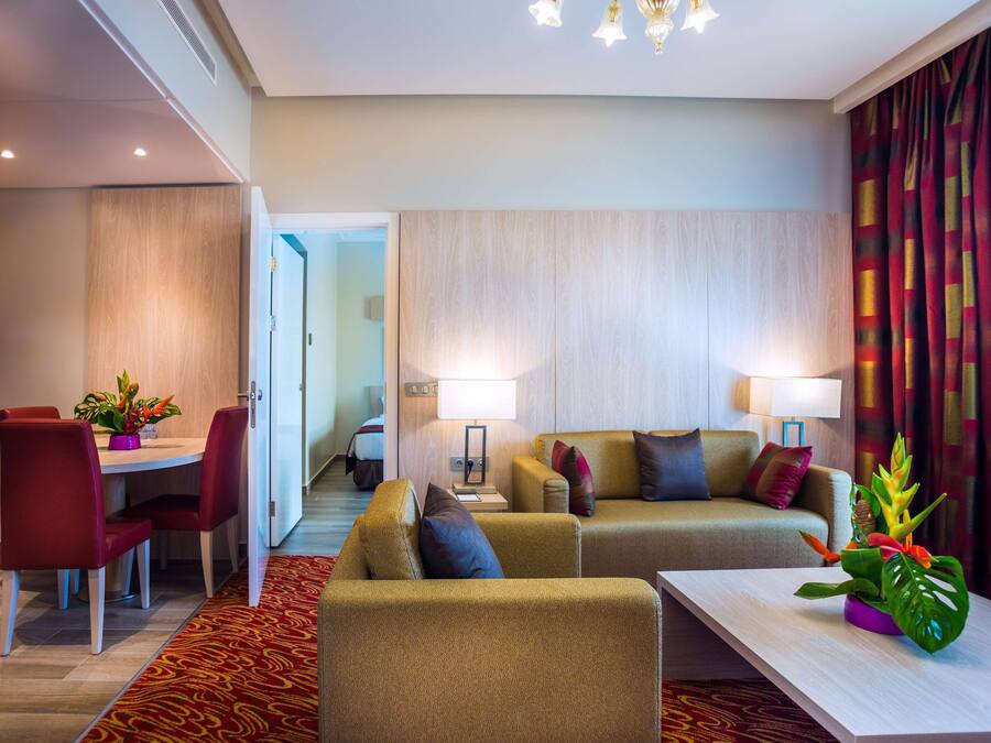 Ein Hotelzimmer mit Essbereich, zwei Sofas, einem Couchtisch und einer Pflanze.