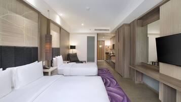 A modern hotel room with a large bed, a desk, a chair, a television, and a bathroom visible in the background.