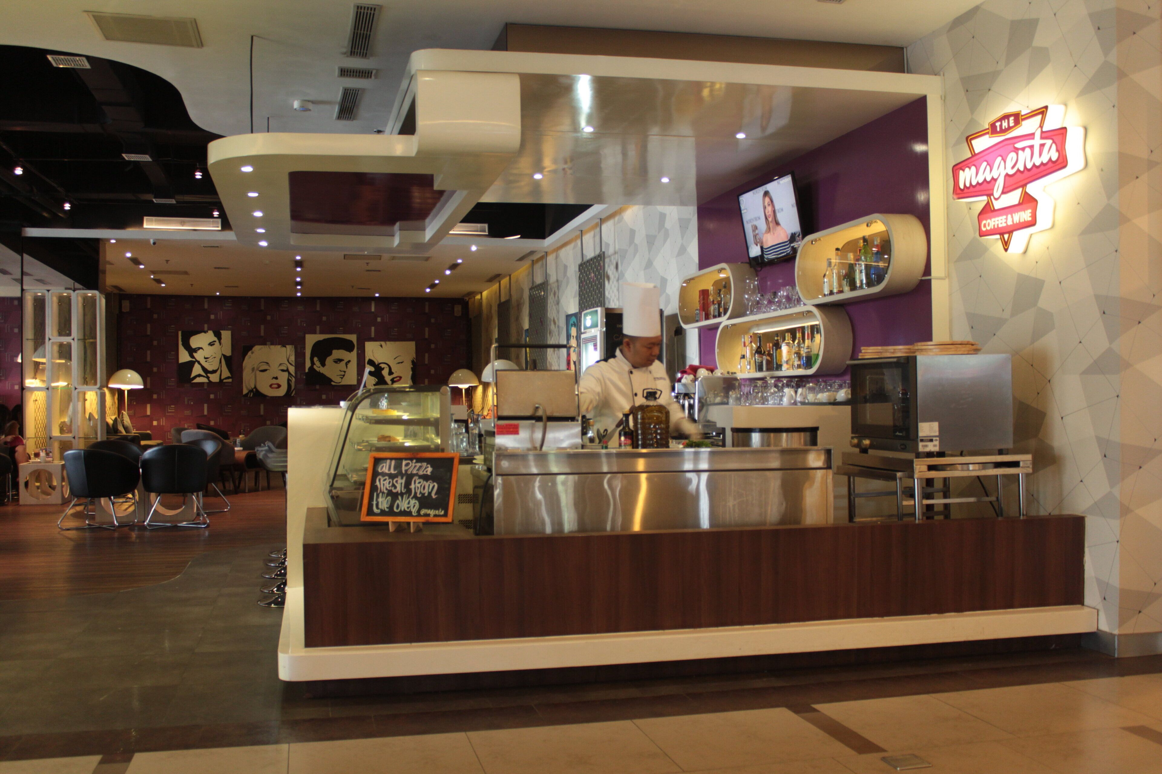 A modern coffee and wine shop with a counter, a chef, and a neon sign.