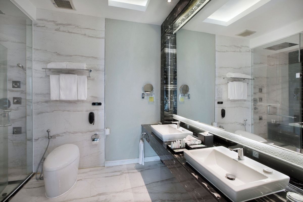 Un bagno moderno con due lavabi, uno specchio grande e una cabina doccia in vetro.