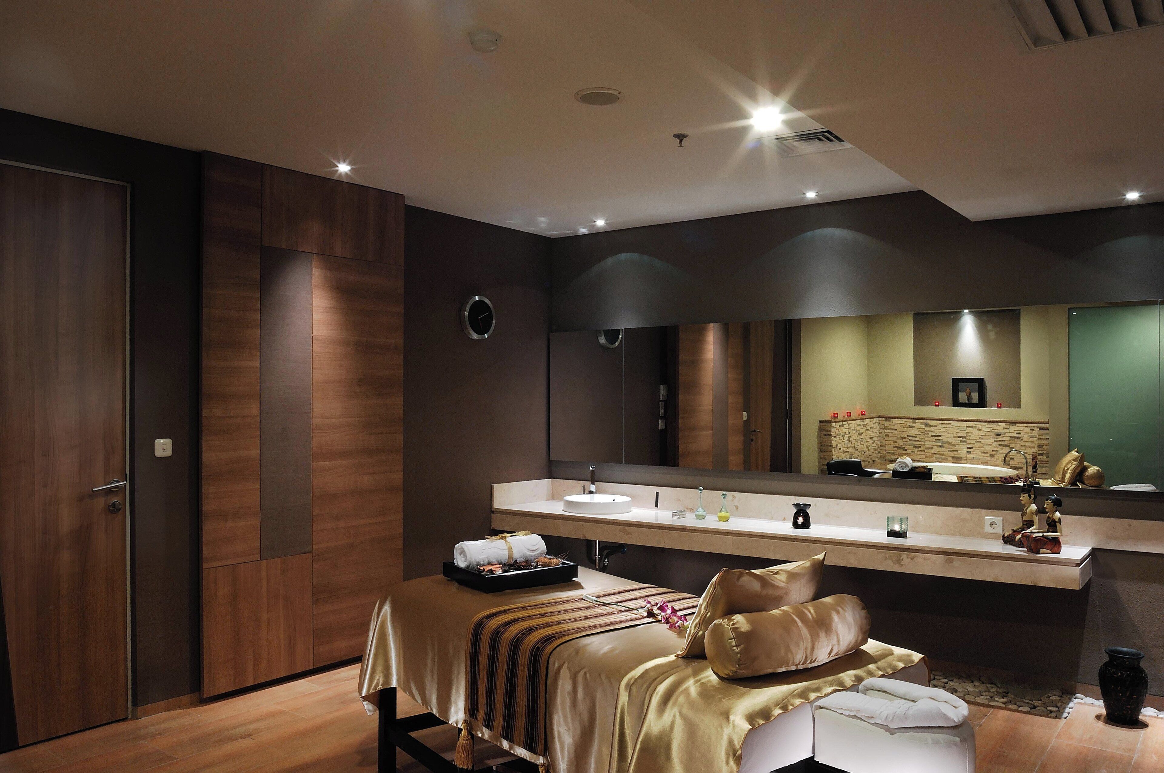 A modern bathroom with a large mirror, a sink, and a massage table.