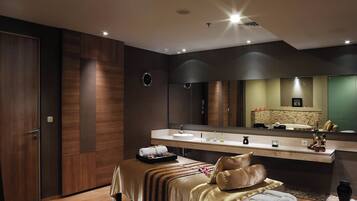 A modern bathroom with a large mirror, a sink, and a massage table.
