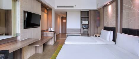 Una habitación de hotel moderna con una cama grande, un escritorio con televisor de pantalla plana, un minibar y una zona de estar con sofá y sillones.