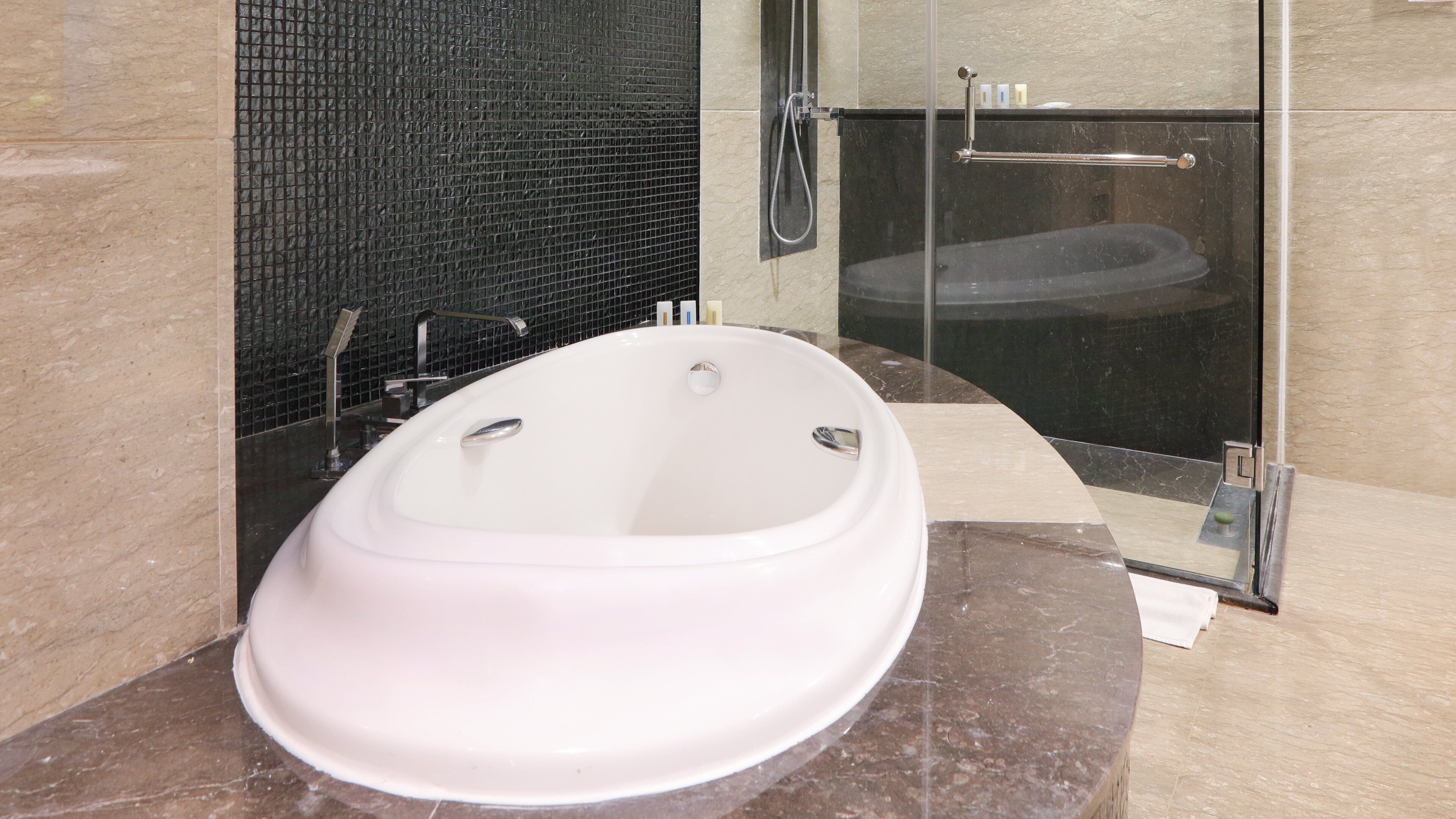 A modern bathroom with a freestanding bathtub, a glass shower enclosure, and a marble-tiled floor.