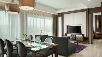 Una habitación de hotel moderna con comedor, televisión de pantalla plana y zona de estar.